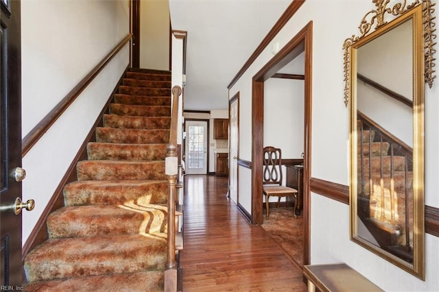 stairs featuring ornamental molding and hardwood / wood-style floors