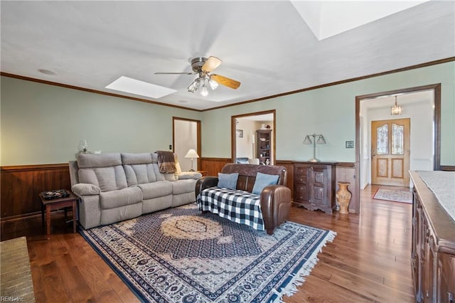 living room featuring ceiling fan, dark wood-type flooring, a skylight, and crown molding