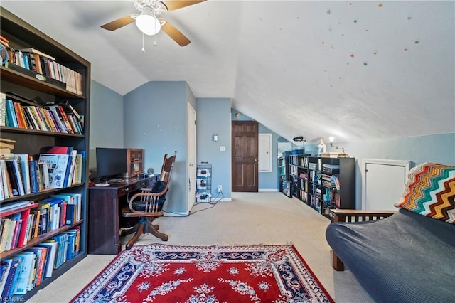 home office featuring light carpet, vaulted ceiling, and ceiling fan