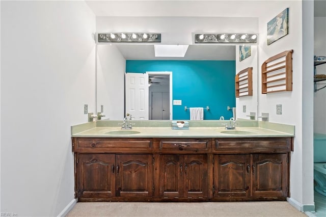 bathroom featuring ceiling fan, a skylight, and vanity