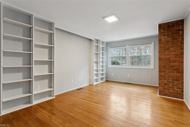 spare room featuring light hardwood / wood-style floors and built in shelves