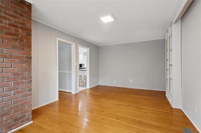 unfurnished room with light wood-type flooring and crown molding