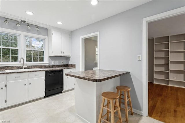 kitchen featuring sink, black dishwasher, a kitchen breakfast bar, kitchen peninsula, and white cabinets