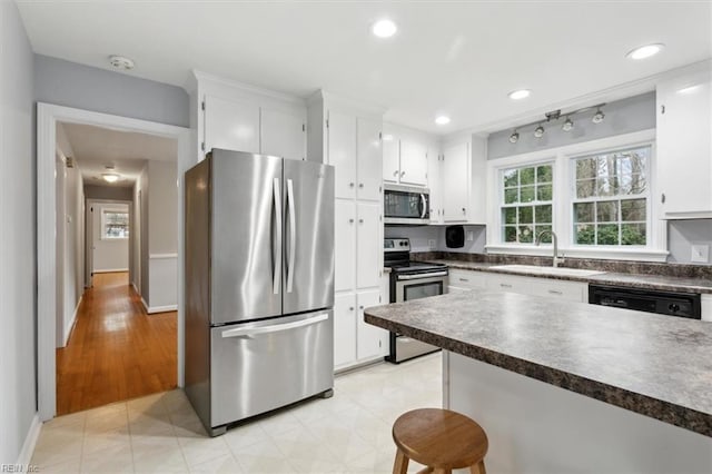 kitchen with appliances with stainless steel finishes, sink, and white cabinetry