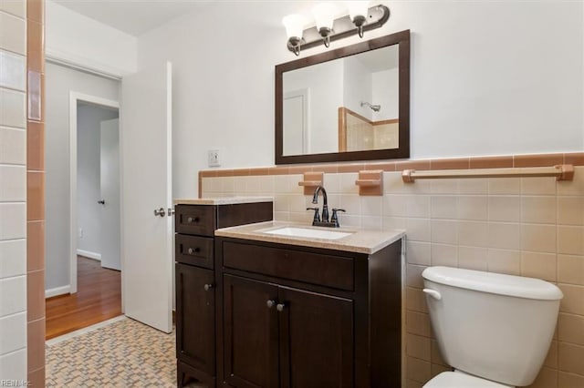 bathroom with tile walls, toilet, and vanity