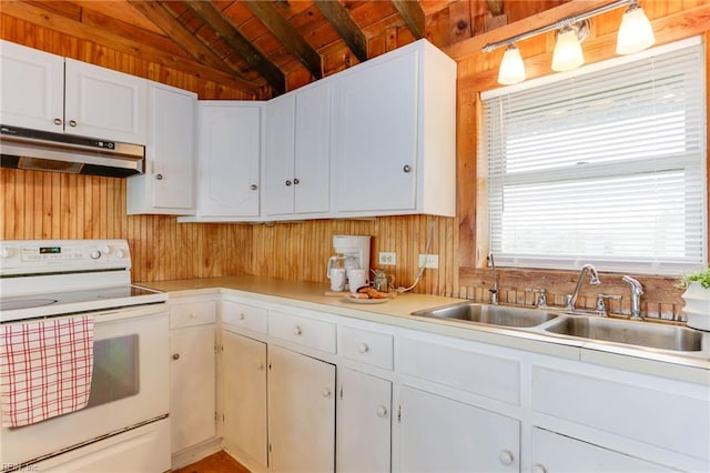 kitchen featuring white range with electric stovetop, hanging light fixtures, wood walls, sink, and white cabinets