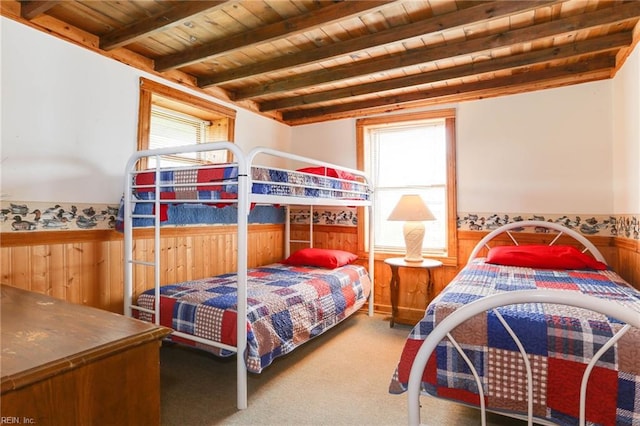 bedroom with beamed ceiling, carpet flooring, wood ceiling, and wooden walls