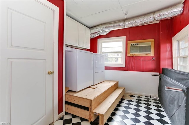 laundry room featuring washing machine and dryer, a wall mounted AC, cabinets, and wooden walls