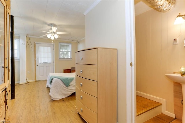 bedroom featuring light wood-type flooring, multiple windows, sink, and crown molding