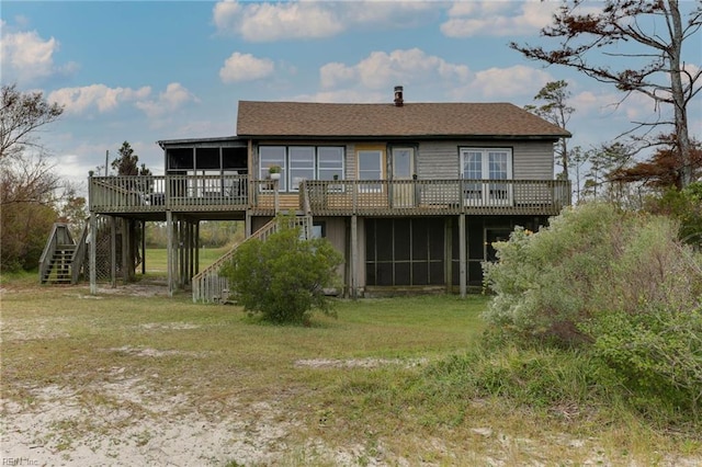 rear view of property with a wooden deck, a lawn, and a sunroom