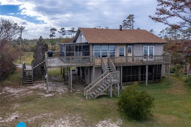 rear view of property featuring a lawn, a sunroom, and a wooden deck