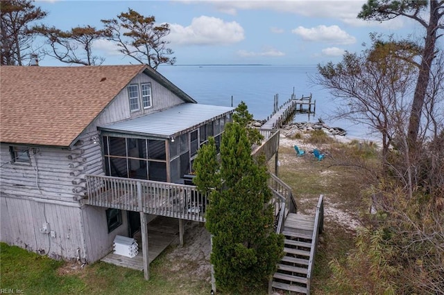 back of property featuring a deck with water view and a sunroom