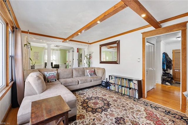 living room with wood-type flooring, crown molding, beamed ceiling, and decorative columns