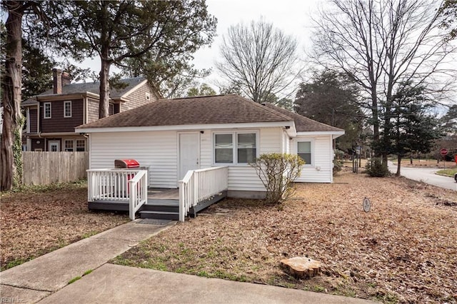 view of front of property with a shingled roof, fence, and a deck