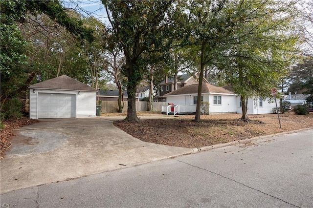 exterior space with a detached garage, fence, a residential view, an outdoor structure, and driveway