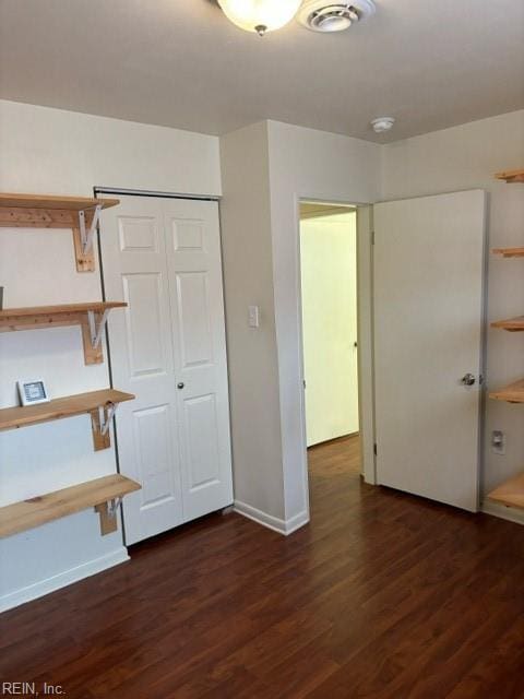 unfurnished bedroom with dark wood-type flooring and a closet