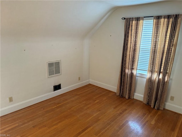 additional living space with vaulted ceiling and wood-type flooring