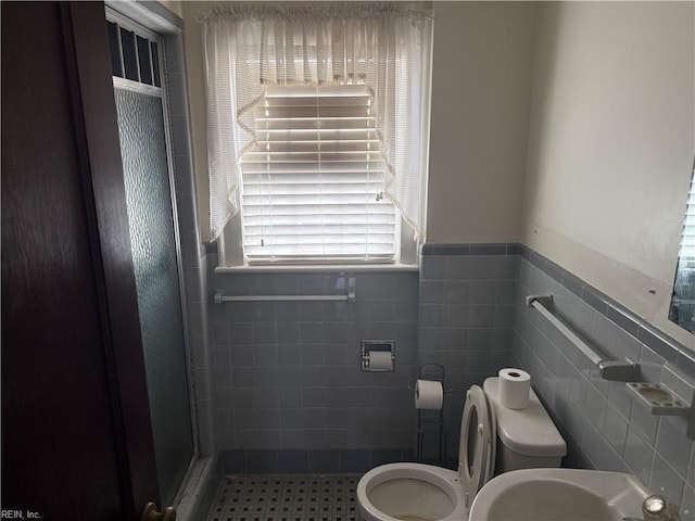 bathroom with tile walls, sink, toilet, and walk in shower