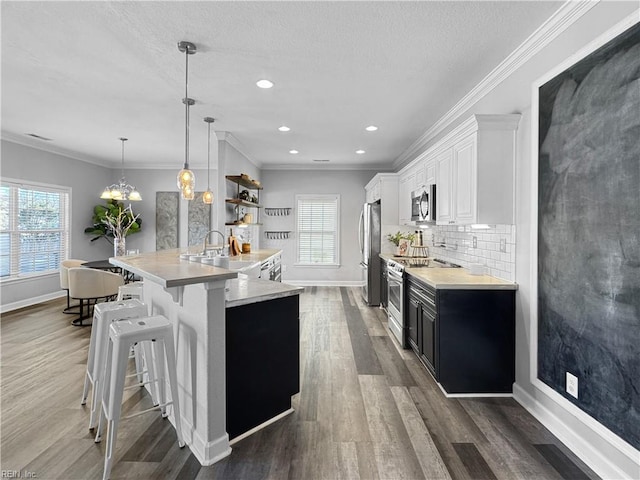 kitchen with stainless steel appliances, white cabinets, decorative light fixtures, a breakfast bar, and backsplash