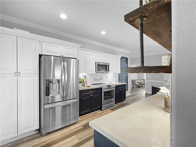 kitchen featuring stainless steel appliances, decorative backsplash, light hardwood / wood-style floors, crown molding, and white cabinetry