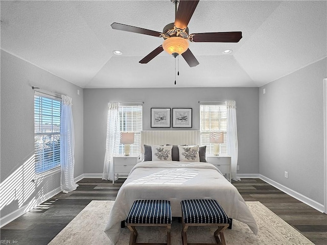 bedroom with vaulted ceiling, multiple windows, and dark hardwood / wood-style floors