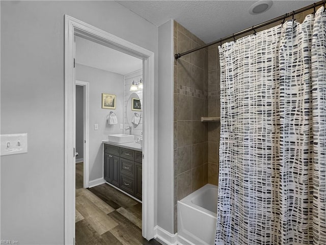 bathroom featuring a textured ceiling, vanity, hardwood / wood-style floors, and shower / bath combination with curtain