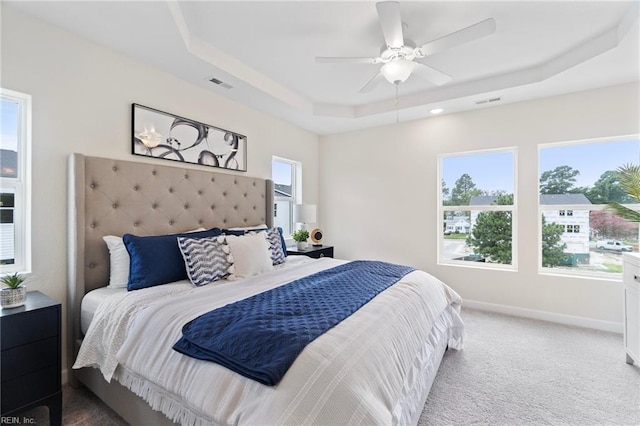 bedroom with a tray ceiling, carpet, and ceiling fan