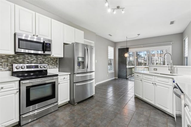 kitchen with appliances with stainless steel finishes, sink, backsplash, pendant lighting, and white cabinets