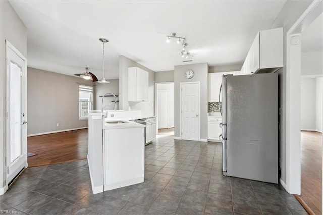 kitchen with white cabinetry, kitchen peninsula, sink, appliances with stainless steel finishes, and decorative backsplash