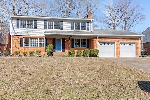 traditional-style house featuring brick siding, a chimney, an attached garage, driveway, and a front lawn