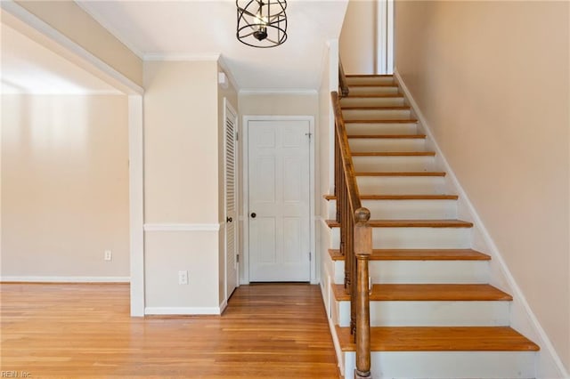 staircase with ornamental molding, baseboards, and wood finished floors