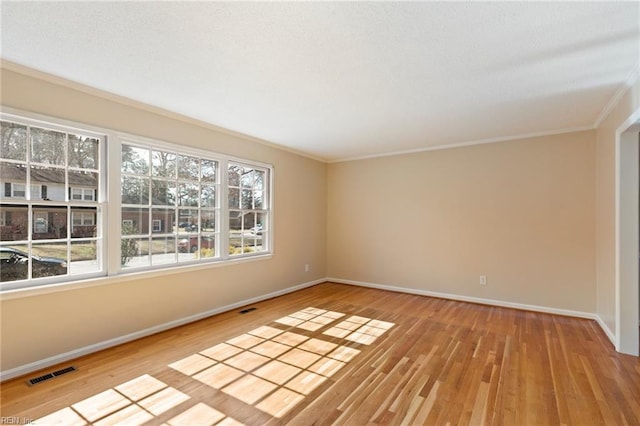 empty room featuring visible vents, baseboards, and wood finished floors