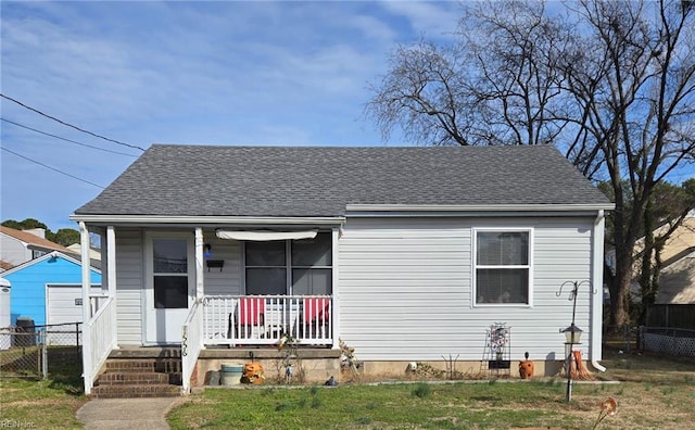 bungalow-style house featuring a shingled roof, covered porch, fence, and a front lawn