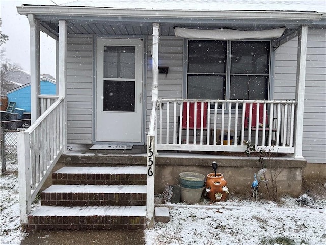 snow covered property entrance with covered porch