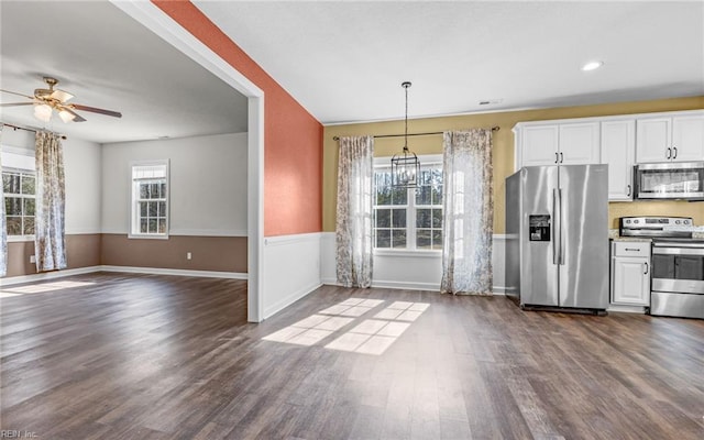 kitchen with dark wood-type flooring, white cabinets, stainless steel appliances, and decorative light fixtures