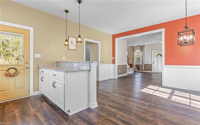 kitchen with a healthy amount of sunlight, white cabinetry, pendant lighting, and light stone counters