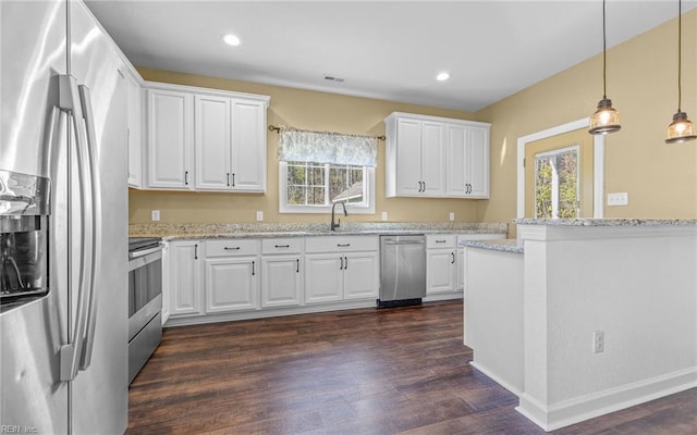 kitchen featuring stainless steel appliances, white cabinetry, and pendant lighting