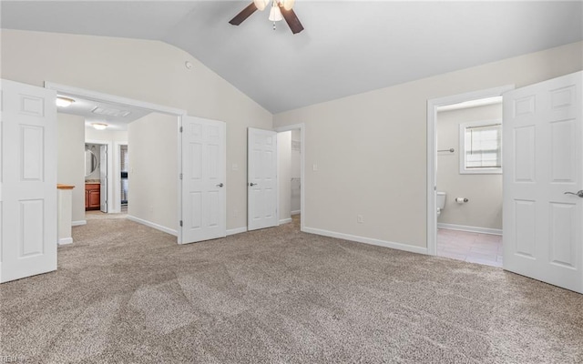 unfurnished bedroom featuring lofted ceiling, ensuite bathroom, light colored carpet, and ceiling fan