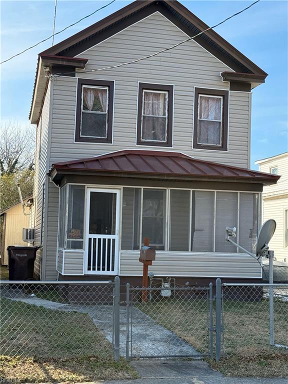 back of house with a sunroom and a lawn