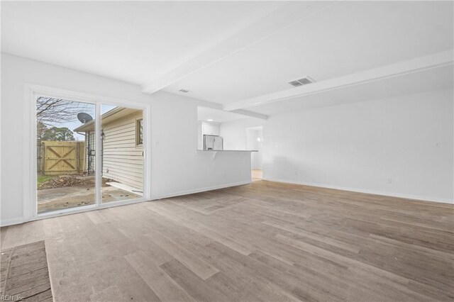 unfurnished living room with baseboards, light wood-style flooring, visible vents, and beamed ceiling