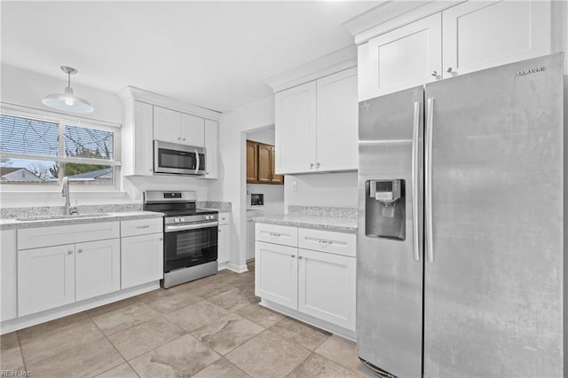 kitchen featuring appliances with stainless steel finishes, a sink, white cabinetry, and light stone countertops