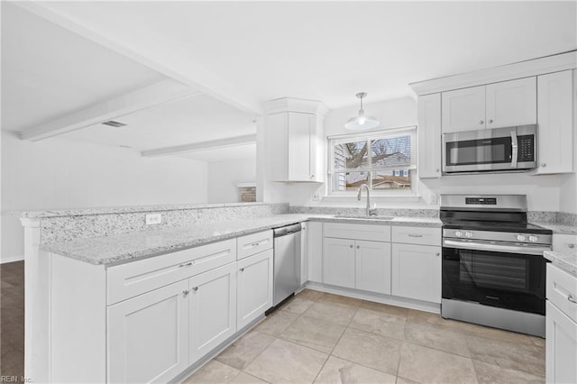 kitchen featuring a peninsula, a sink, white cabinets, appliances with stainless steel finishes, and decorative light fixtures