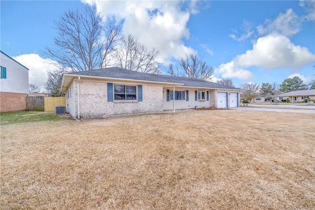 single story home featuring an attached garage, cooling unit, brick siding, fence, and a front yard