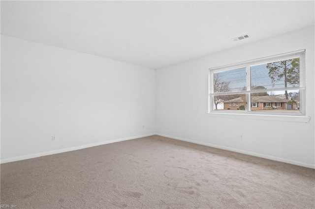 spare room with carpet floors, baseboards, and visible vents