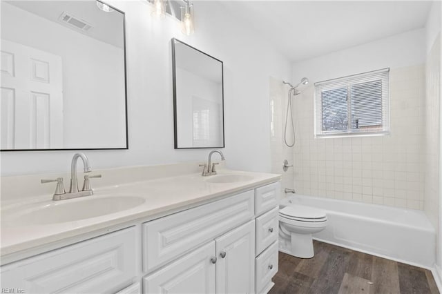 bathroom featuring shower / bathtub combination, wood finished floors, a sink, and visible vents