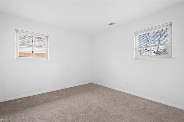 carpeted spare room with visible vents and baseboards