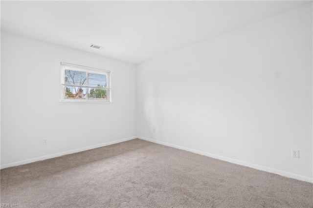 spare room with carpet floors, visible vents, and baseboards