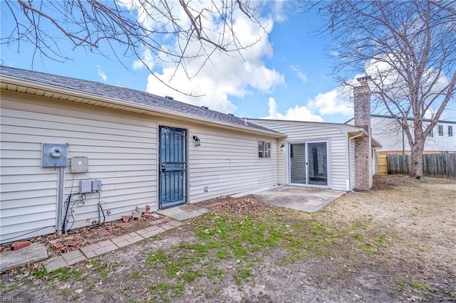 rear view of property with a patio area, fence, and a chimney