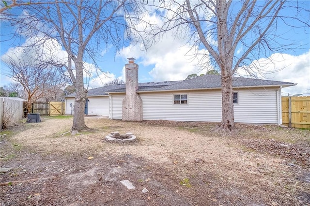 rear view of house featuring an outdoor fire pit, a chimney, and a fenced backyard