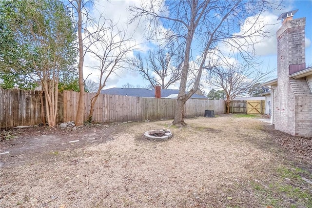 view of yard featuring a fenced backyard, a fire pit, and central AC unit